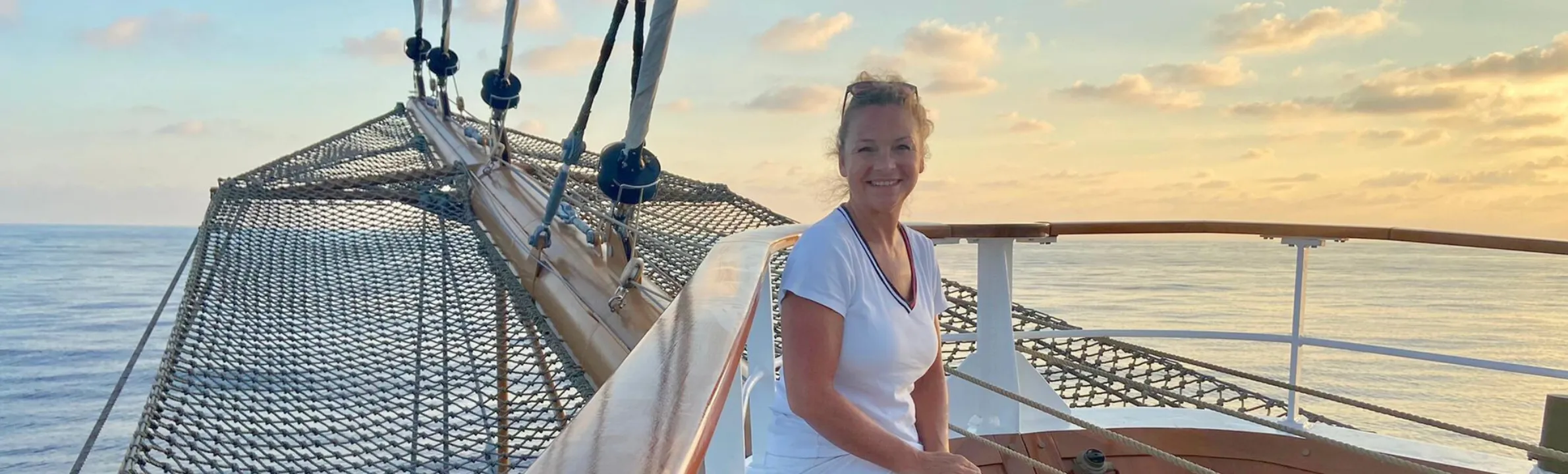 Frau mit Hut lächelt in die Kamera und streckt ihre Arme in Richtung Kamera aus