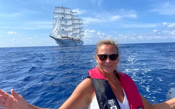 Frau mit Schwimmweste vor großem Segelschiff