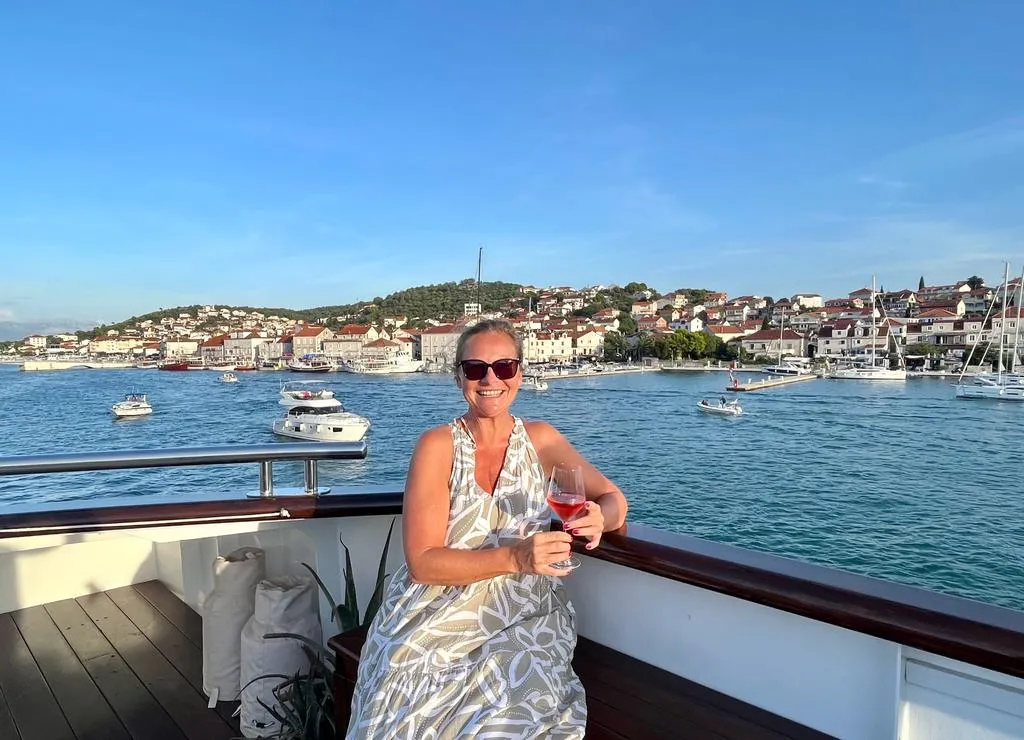 Frau mit Weinglas auf einem Schiff mit Küste von Kroatiens im Hintergrund