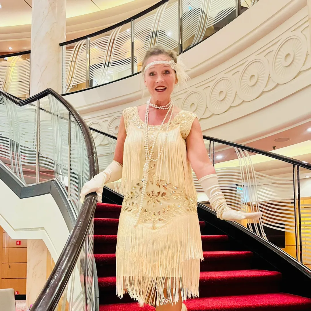 Frau in schickem weißen Kleid auf einer Treppe mit rotem Teppich