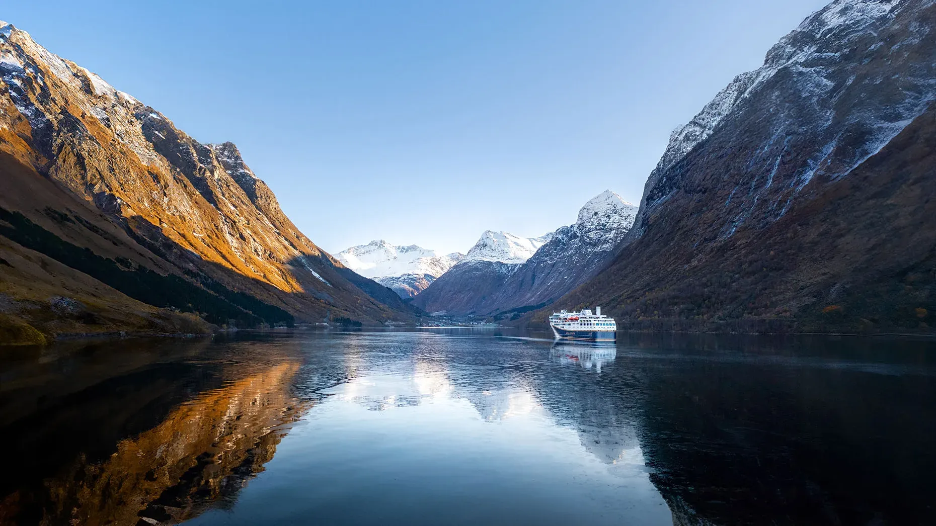 Zwei Personen sitzen in einem Whirlpool auf einem Schiff mit Blick auf einen Fluss und bewaldete Berge