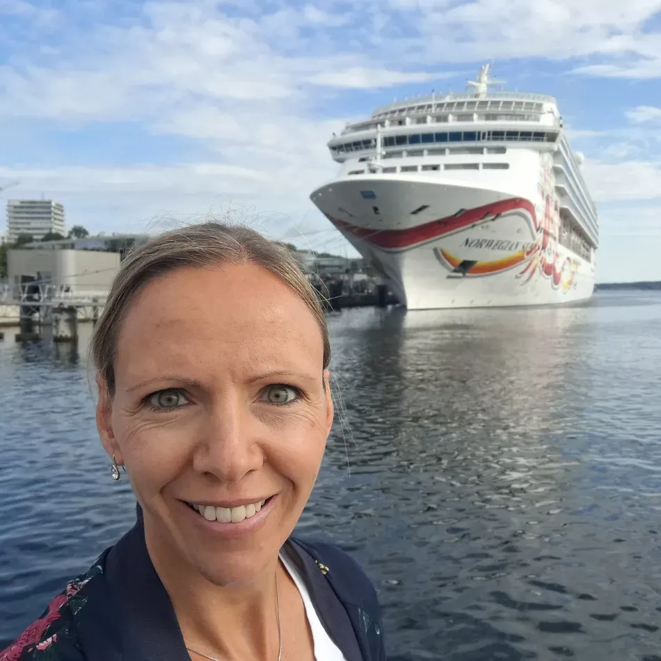Frau macht Selfie vor einem Kreuzfahrtschiff