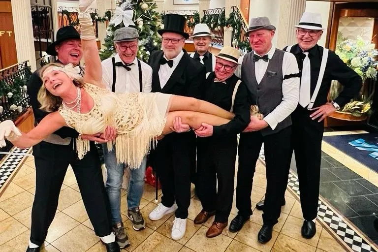 Sieben Männer tragen eine verkleidete Frau