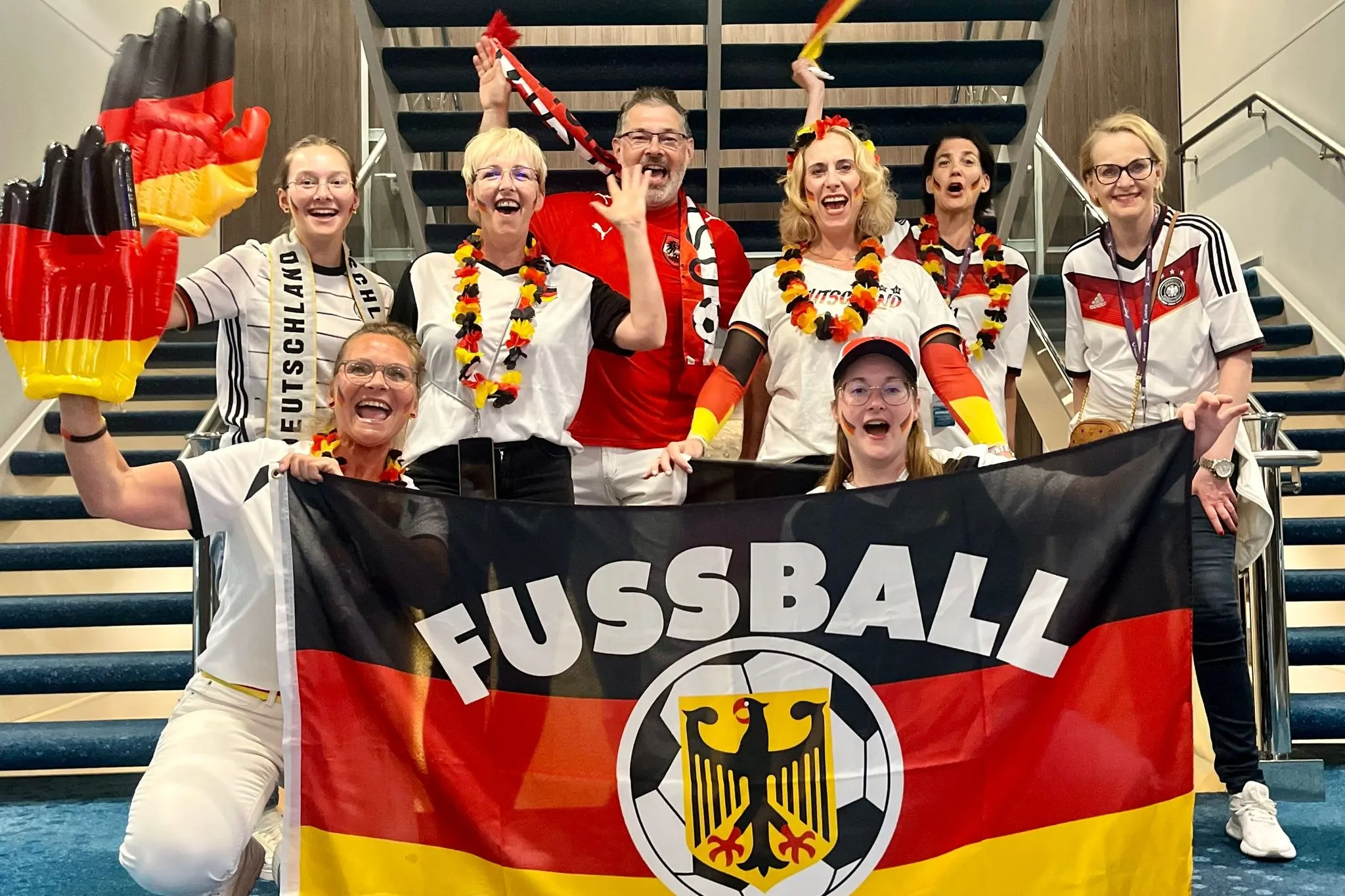 Mehrere Personen sind in den farben rot, gelb, schwarz verkleidet und halten eine Fußball Deutschlandfahne