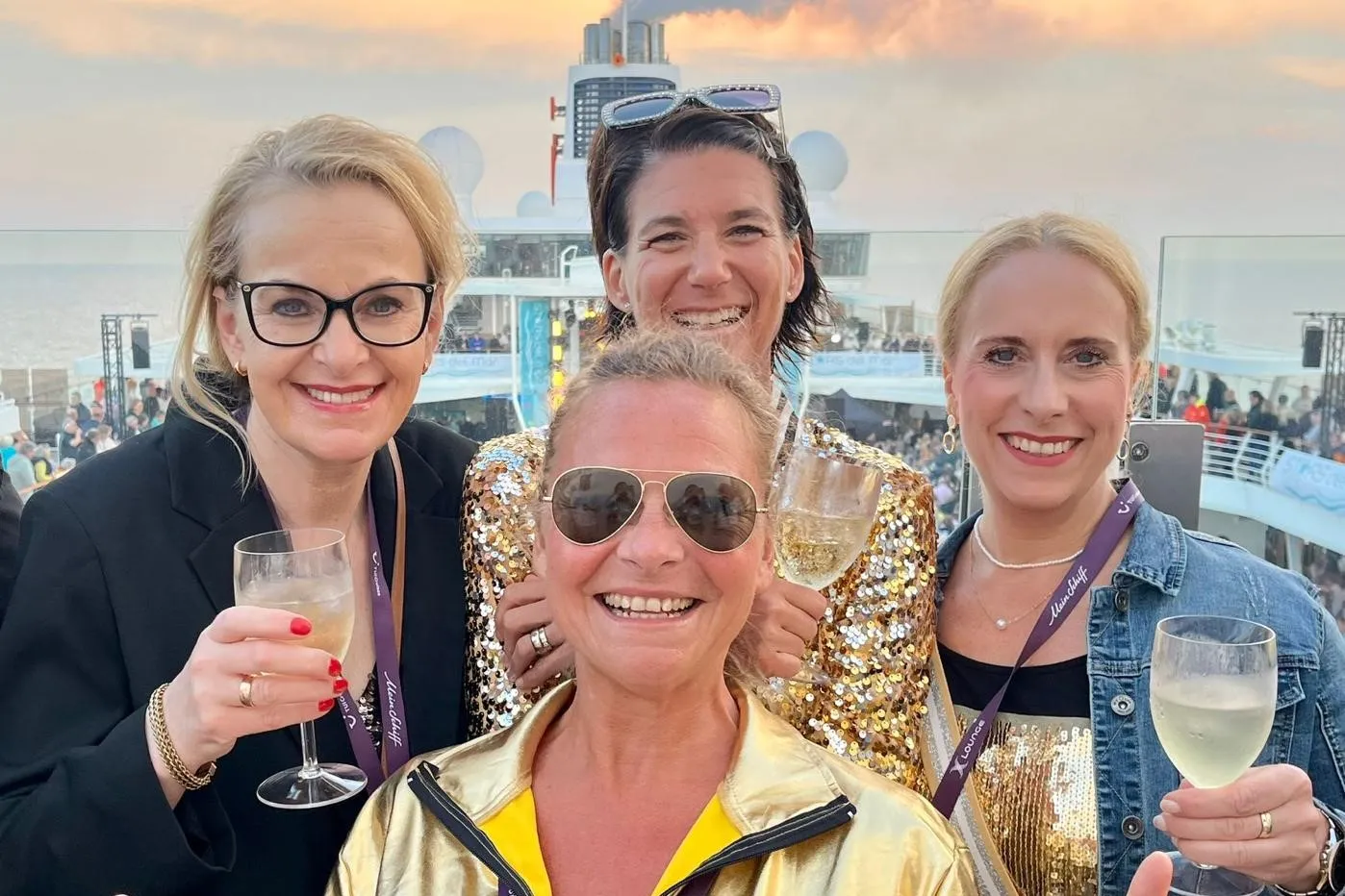 Vier Frauen lachen in die Kamera und halten Weingläser in die Höhe