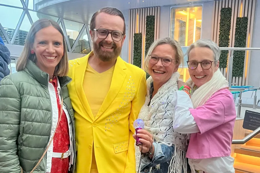 Drei Frauen und ein Mann stehen nebeneinander und lachen in die Kamera