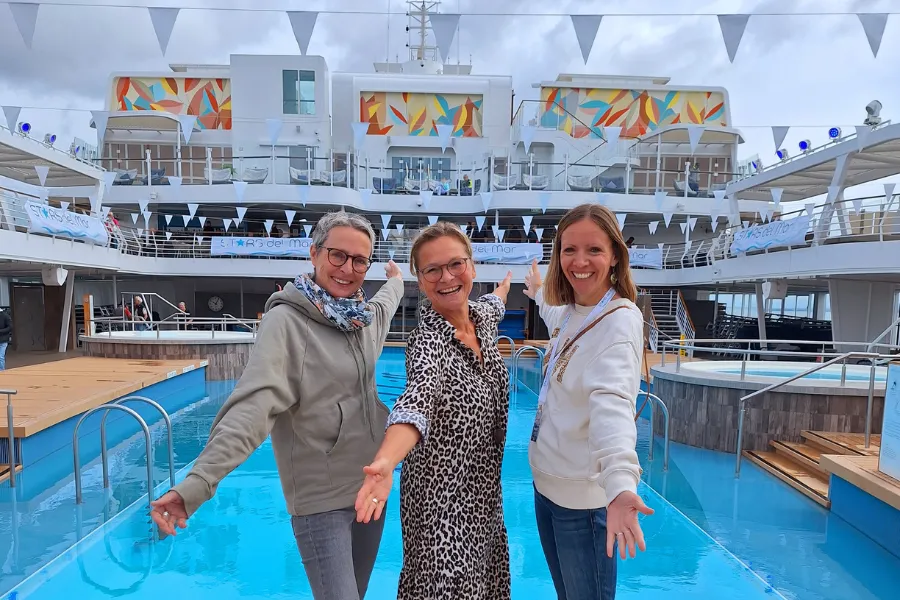 Drei Frauen stehen vor dem Pool auf einem Kreuzfahrtschiff