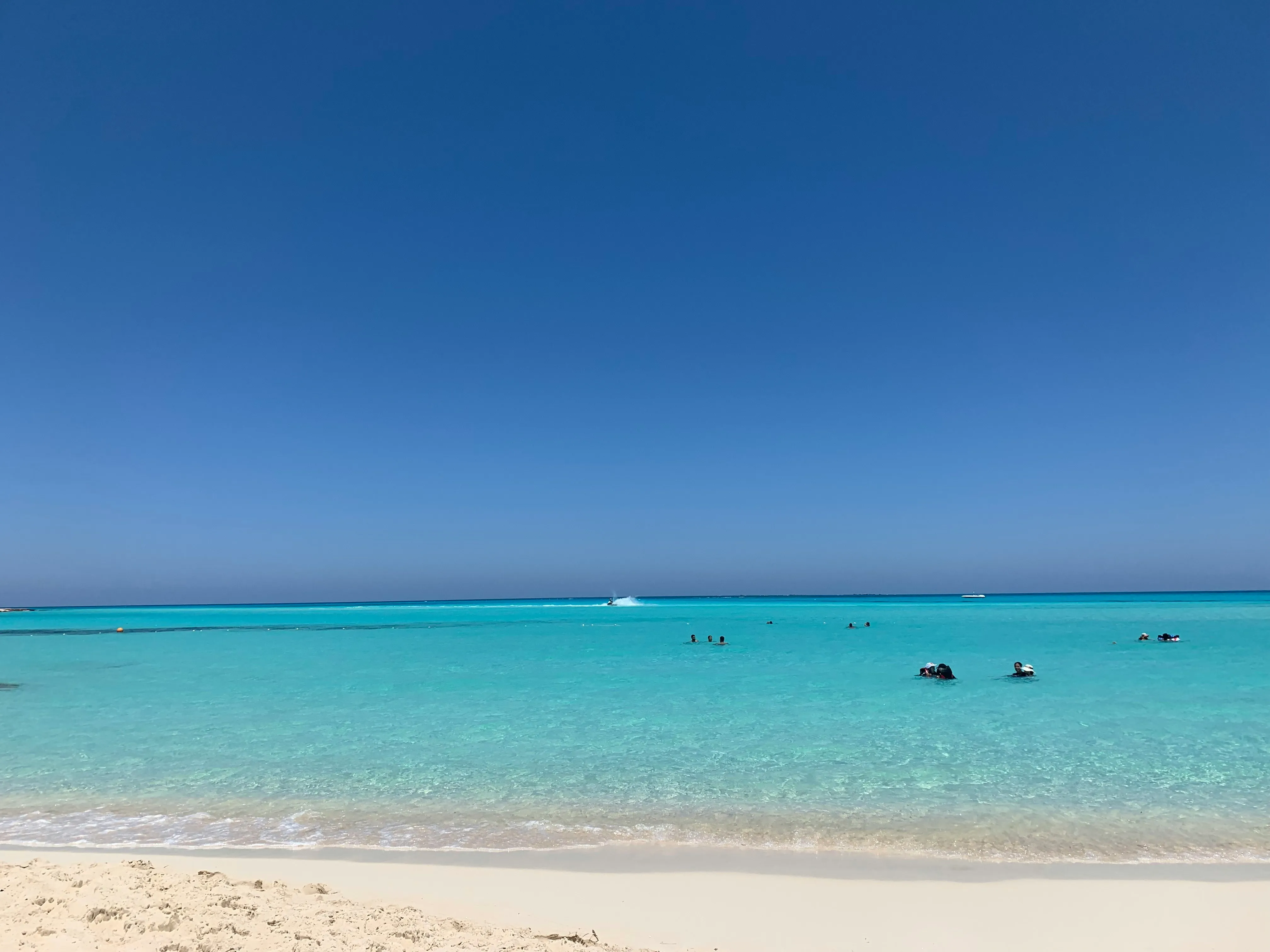Strand mit hellem Sand und türkisfarbenem Meer unter klarem Himmel