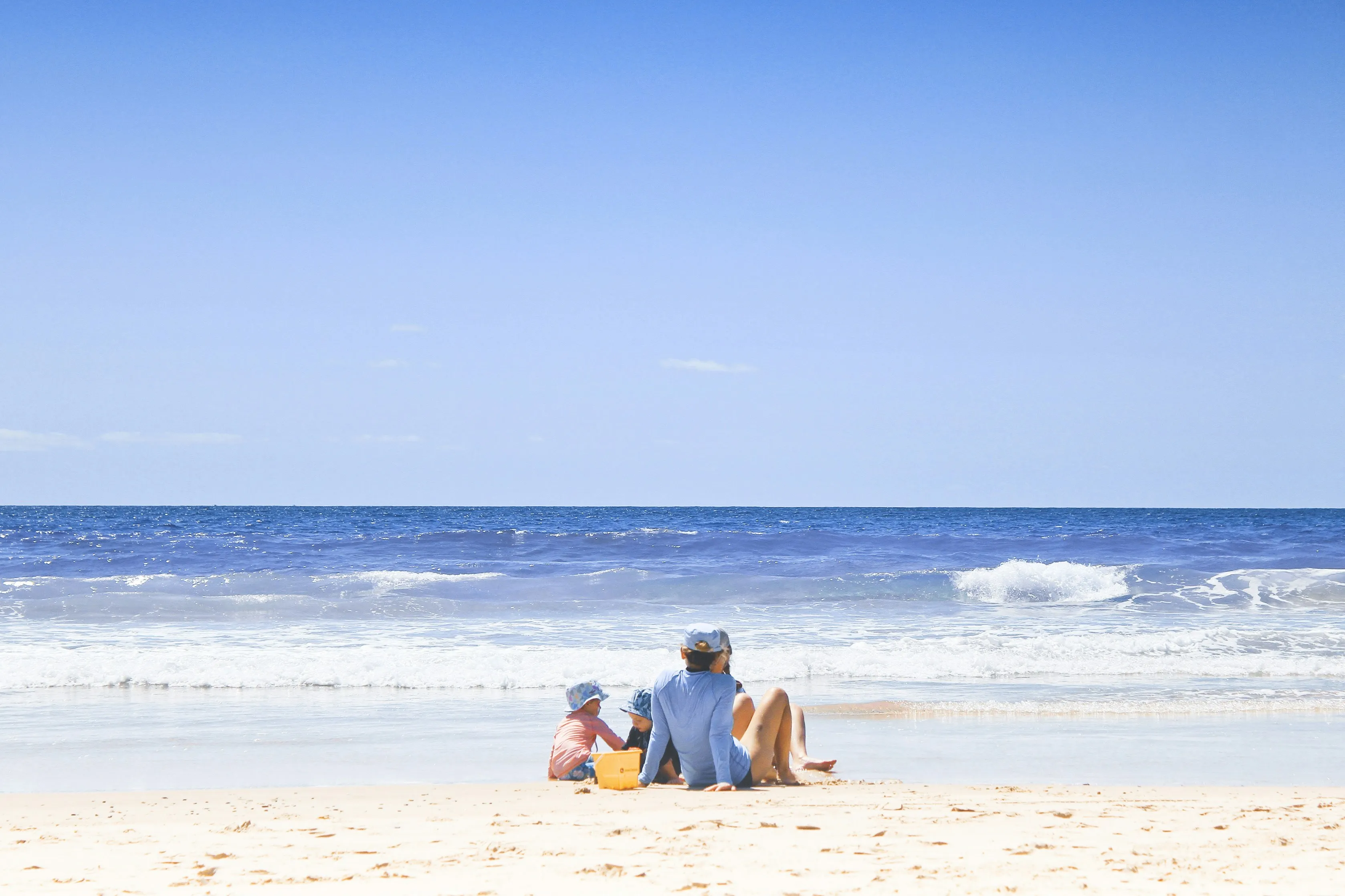 Kinder sitzen am Strand und spielen im Sand