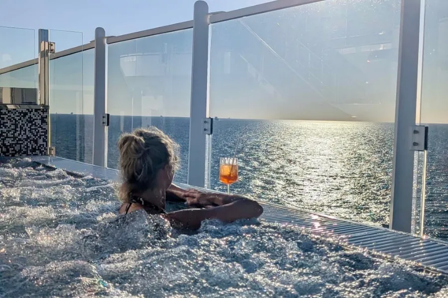 Frau im Whirlpool eines Kreuzfahrtschiffs schaut aufs Meer