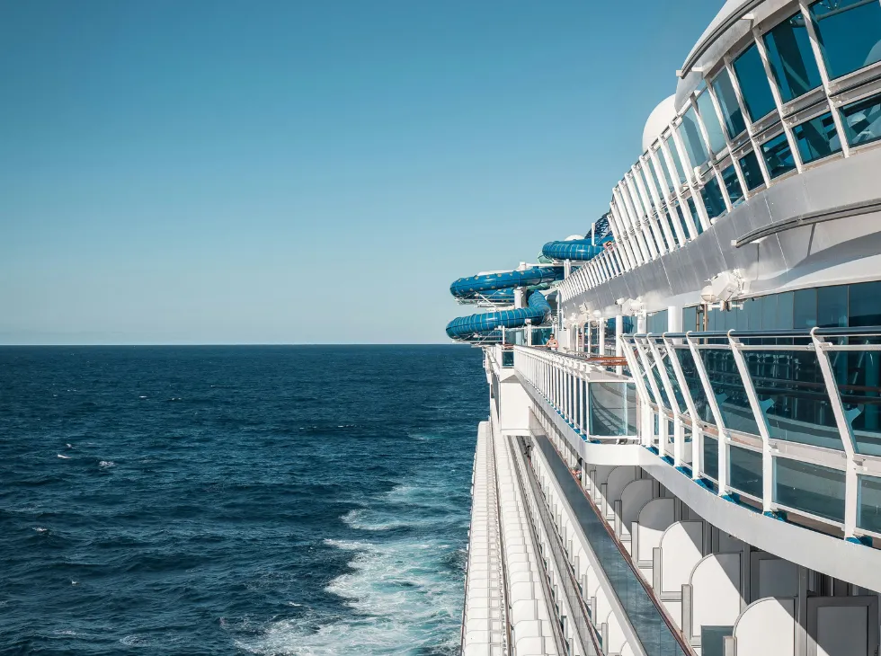Seitenansicht eines Kreuzfahrtschiffs mit sichtbaren Wasserrutschen und Geländern auf dem Deck im offenen Meer