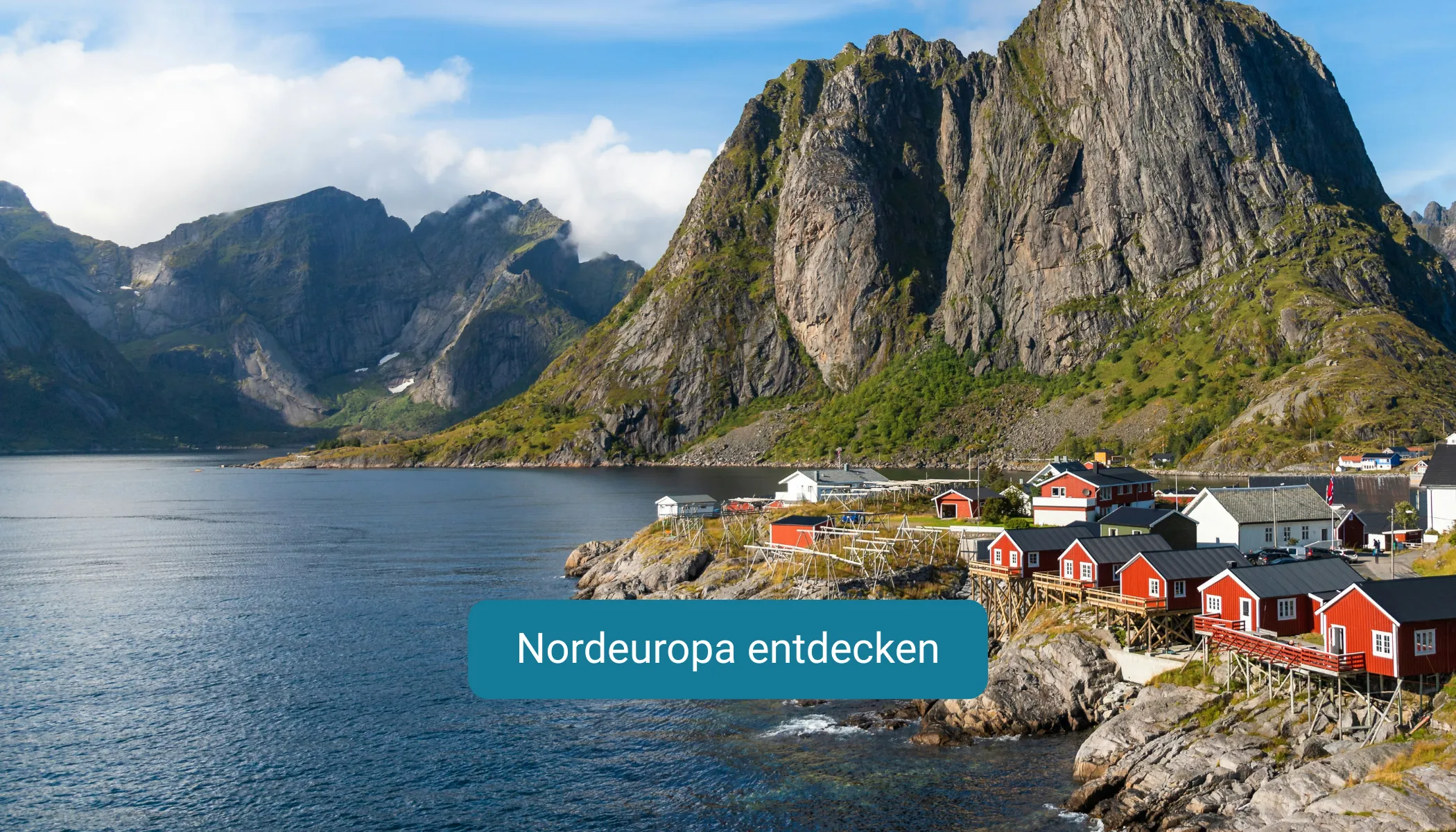 Rote Häuser stehen am Rand des Fjordes im Hintergrund hohe Berge